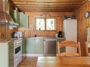 Una cucina compatta con pareti in legno, un fornello, un lavandino e un frigorifero.