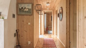 A wooden hallway with a rug, a painting, and a mirror.