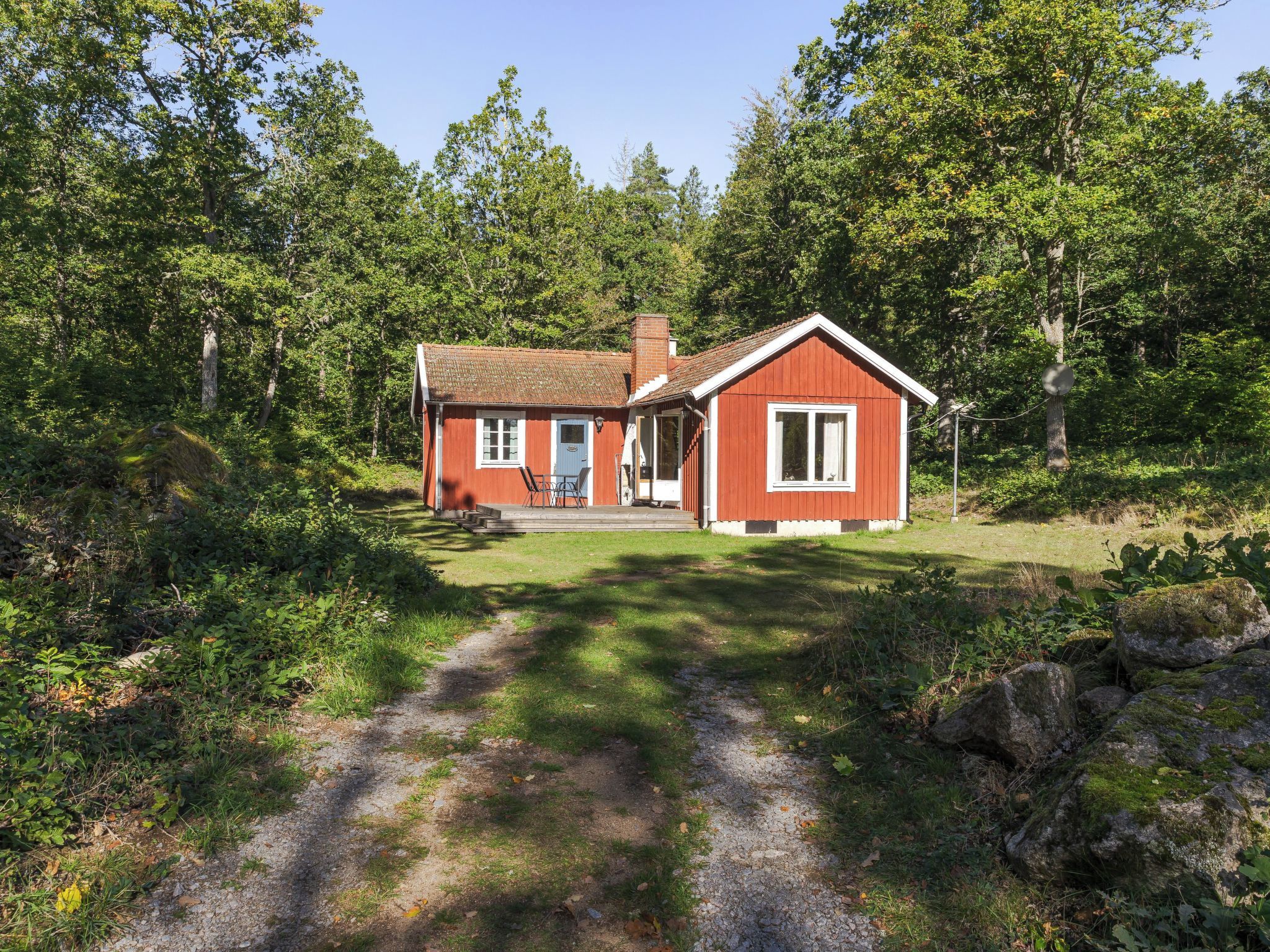 Une maison en bois rouge avec un porche et un petit jardin.