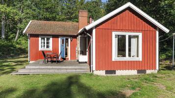 Ett rött trähus med en veranda, en dörr och ett fönster.