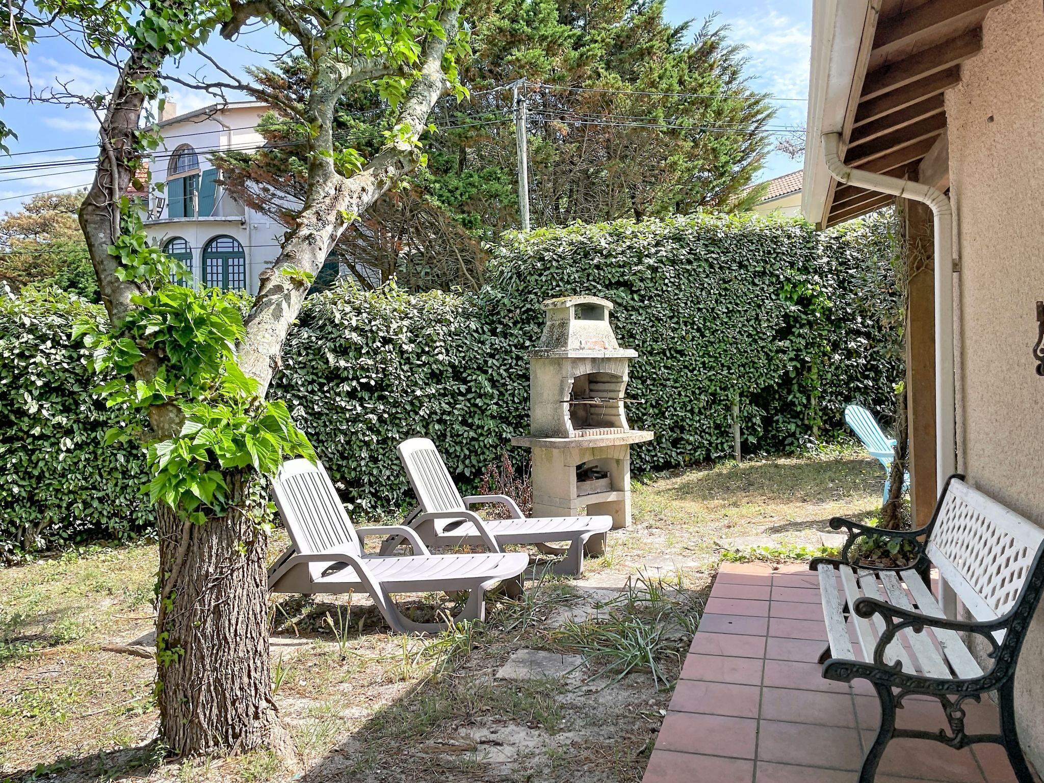 Un patio con dos sillones de descanso, un horno de piedra y un banco.