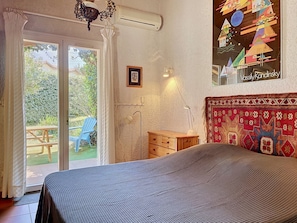 Un dormitorio con una cama, una ventana con cortinas, un aparador de madera y un tapiz decorativo en la pared.