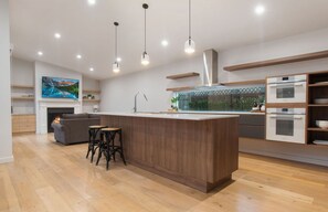 Enjoy cooking in the well-equipped kitchen with a sink and stainless steel range hood, then relax in the adjacent living area with a comfortable sofa and flat-screen TV.