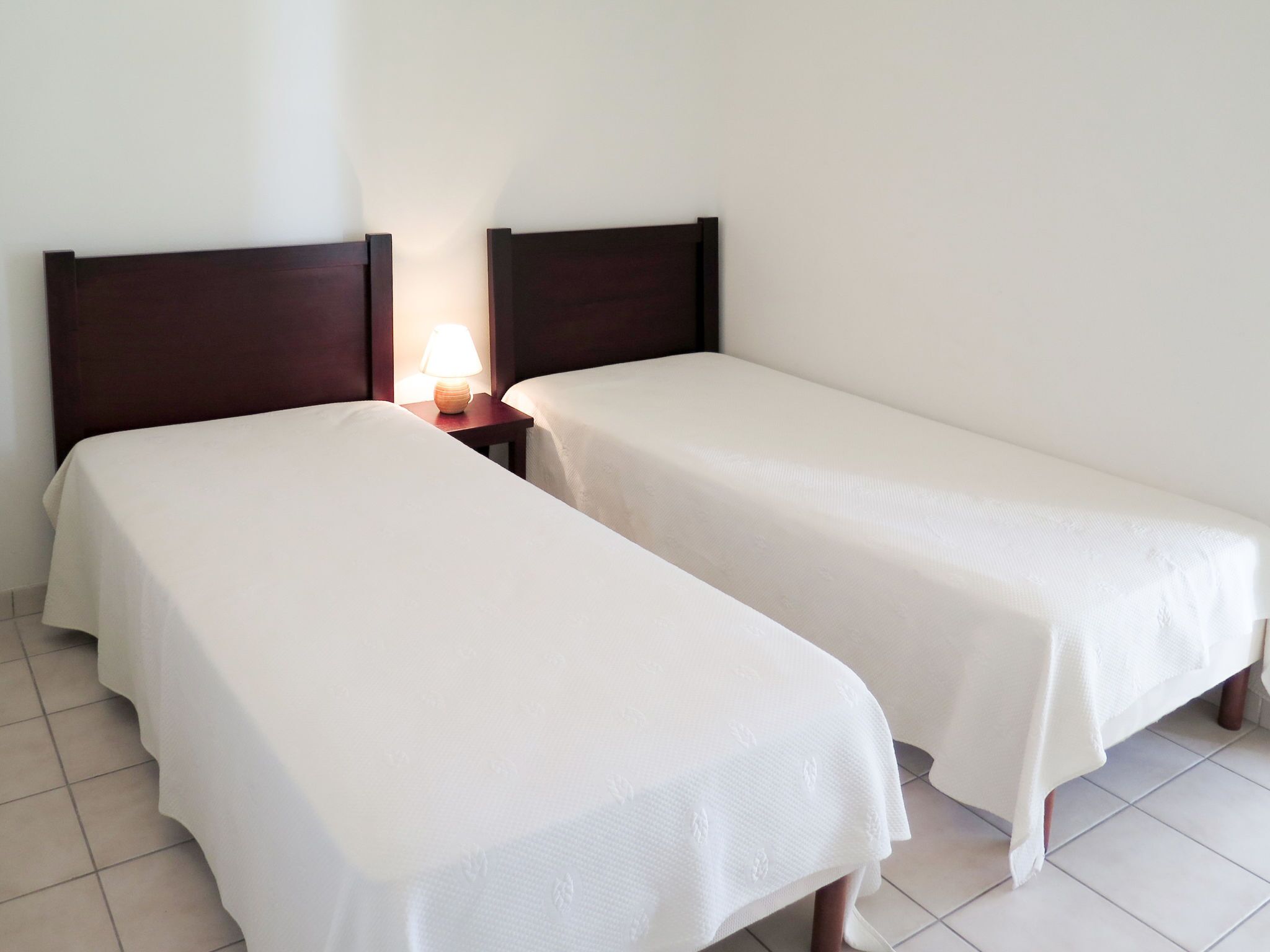 Two single beds with wooden headboards and white linens in a hotel room.