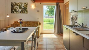 A modern kitchen with a dining area, wooden ceiling, and a view of the outdoors. - Gelsomino by Interhome (Dongo)