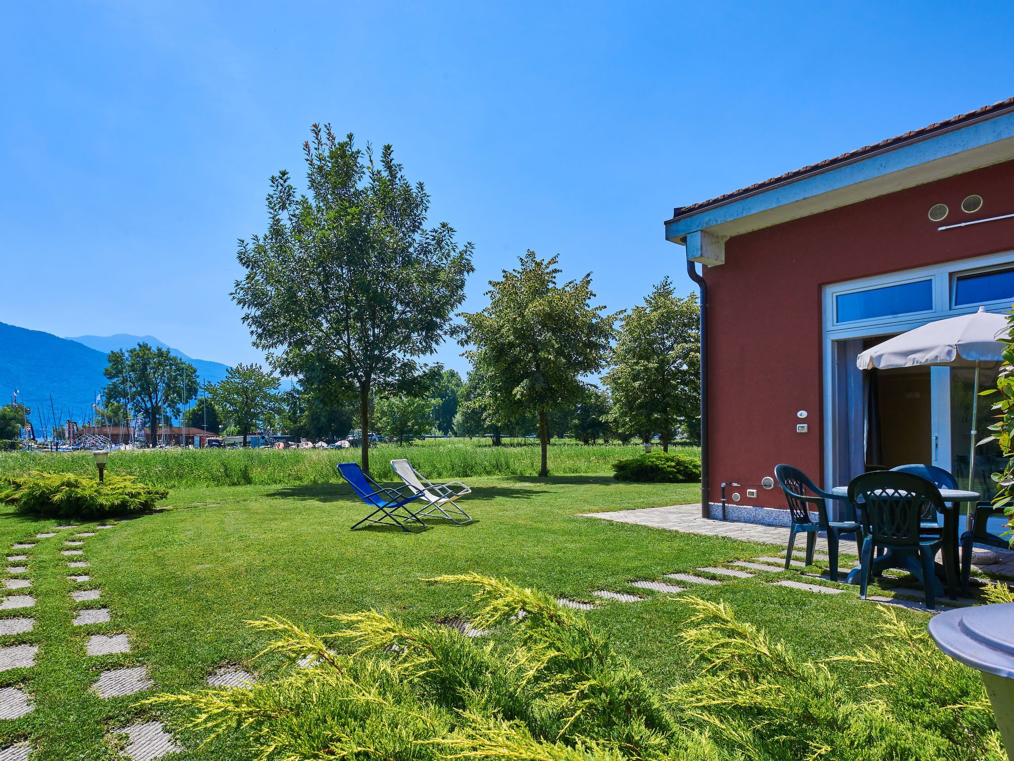 A hotel with a red exterior, a patio with outdoor seating, and a view of mountains in the background.