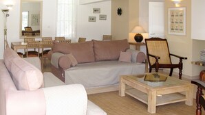 A living room with a sofa, armchairs, a coffee table, a dining table with chairs, and a lamp.