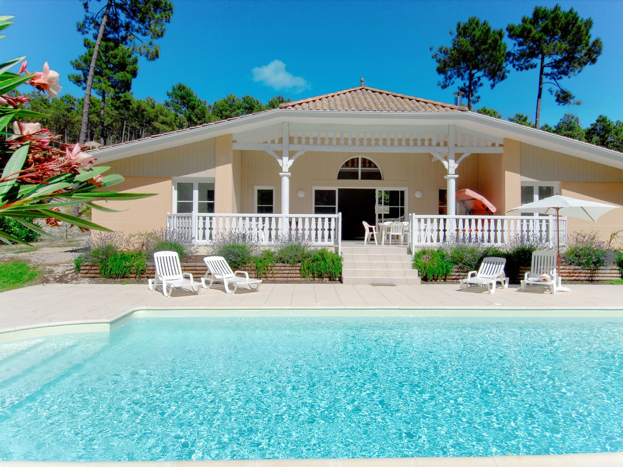 Uma casa com piscina, cadeiras brancas e um espaço de varanda coberto.