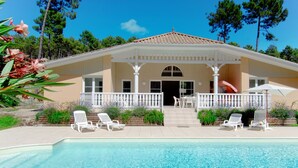 Ein Haus mit Pool, weißen Stühlen und einer überdachten Terrasse.