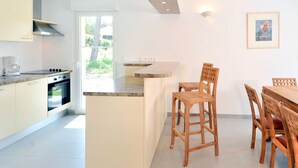 Een moderne keuken met een centraal eiland, houten stoelen en een eettafel.