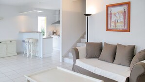 A modern living room with a sofa, a coffee table, and a kitchen in the background. - Eden Parc Golf de l'Ardilouse V8I by Interhome (Lacanau)