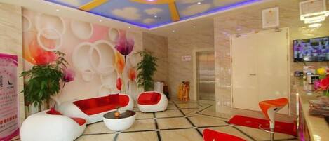A lobby with a modern design, featuring a reception desk, seating area with sofas and chairs, and decorative wall art.
