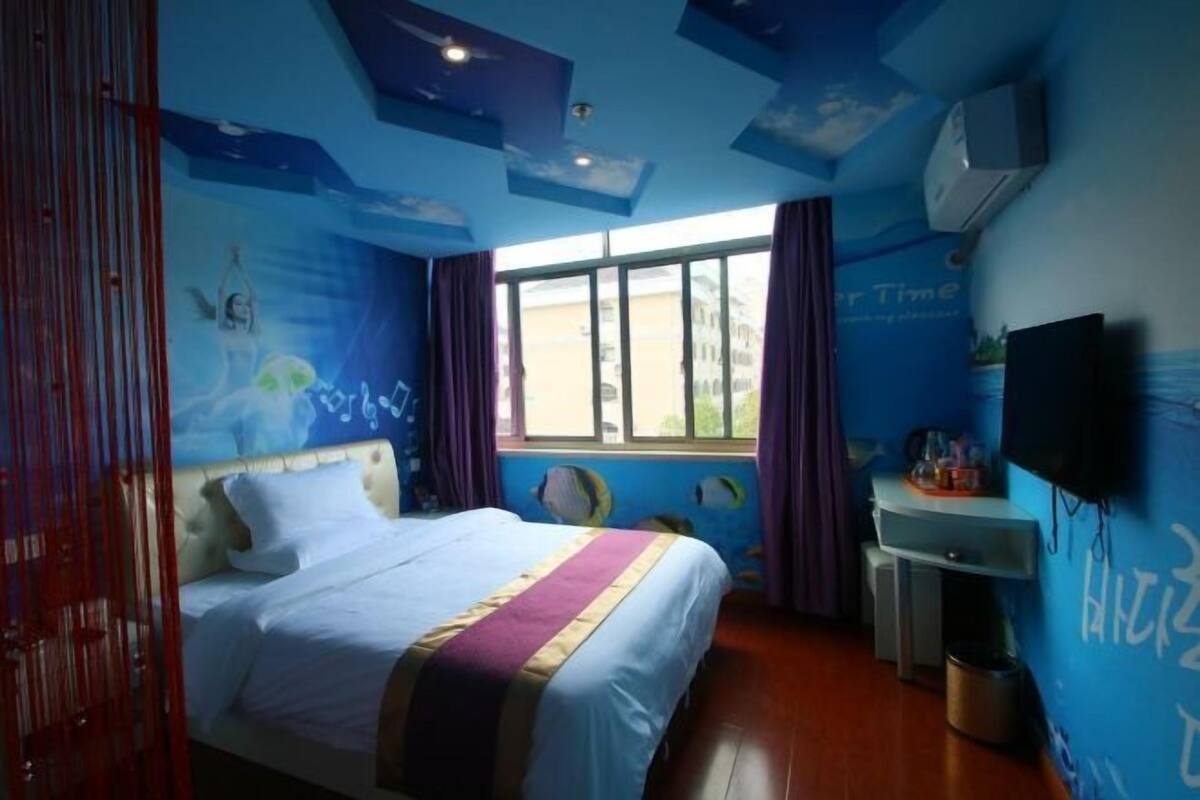 A bedroom with a bed, a desk, a window, and a wall with a mural.