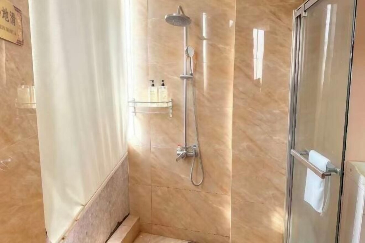 A bathroom with a glass shower enclosure, a towel rack, and a shelf with toiletries.