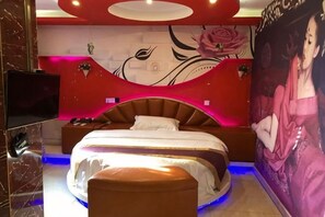 A bedroom with a bed, a television, and a wall with a large painting. - Light Stay·Noli Theme Hotel (Shanghai Fengxian Nanqiao Branch) (Shanghai)