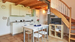 Une cuisine moderne avec des meubles blancs, une table à manger avec des chaises et un escalier en bois.