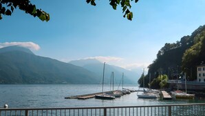 Une vue sur le lac, avec des bateaux amarrés à un quai, le tout entouré de montagnes et sous un ciel dégagé.