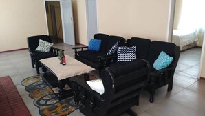 A room with a sofa set, a small table, and a patterned rug. There are doors and a window in the background.