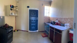 Una cucina compatta con un fornello a gas, una porta blu e una piccola finestra.
