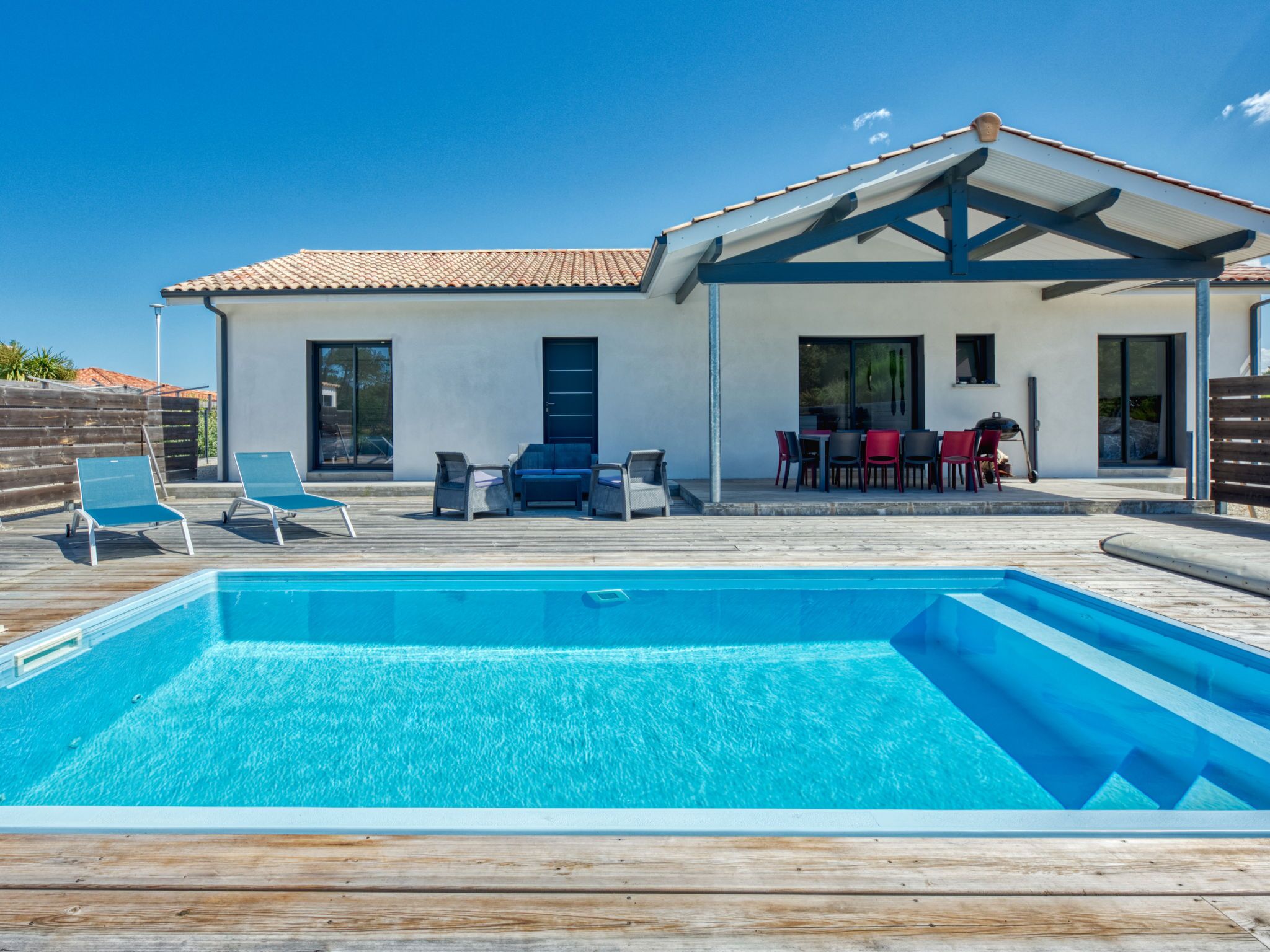 A modern house with a swimming pool, outdoor seating, and a patio.