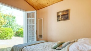 Un dormitorio con una cama, un ventanal con vistas a zonas verdes y un cuadro en la pared.