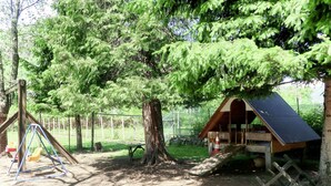 Un parque infantil con columpios y una pequeña estructura de madera con techo inclinado.