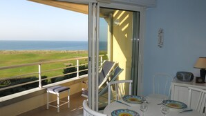 Varanda com mesa posta para dois, com vista para a paisagem costeira.