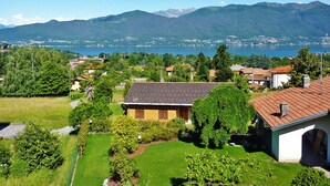 Un quartier résidentiel avec des maisons, un jardin et un lac, le tout surmonté de montagnes en arrière-plan.