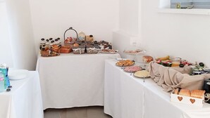 Una habitación con paredes blancas y un techo alto, que incluye un comedor con mesas dispuestas para el desayuno.