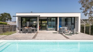A modern house with a swimming pool, a patio with outdoor furniture, and a glass door leading to the pool area. - Villa de la Baie by Interhome (Locquirec)