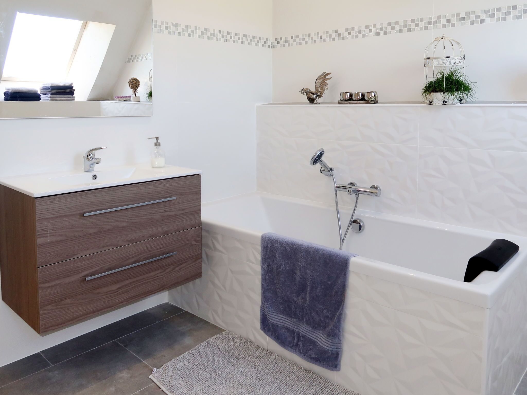Ein modernes Badezimmer mit einem Holzbadschränkchen, einer weißen Badewanne und einer Dusche.