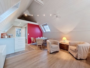 A loft-style room with a sloped ceiling, a dining area with chairs, a small table, and a lamp. - La Belle Vue by Interhome (Locquirec)