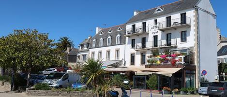 A hotel with a white facade, multiple balconies, and a sign reading "HOTEL DU PORT".