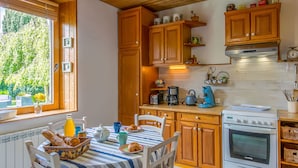 Uma cozinha com armários de madeira, fogão e área de jantar com toalha de mesa listrada.