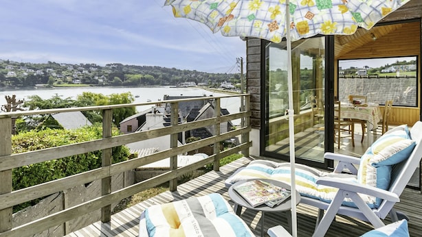 A deck with a view of a lake, a wooden fence, and a table with chairs. - Ti an Aod by Interhome (Plougasnou)