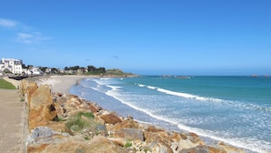 A coastal view with a rocky shoreline, a sandy beach, and buildings in the background. - Ti an Aod by Interhome (Plougasnou)