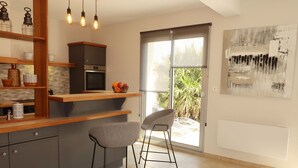 Een moderne keuken met een ingebouwde oven, een houten aanrecht en twee barkrukken.
