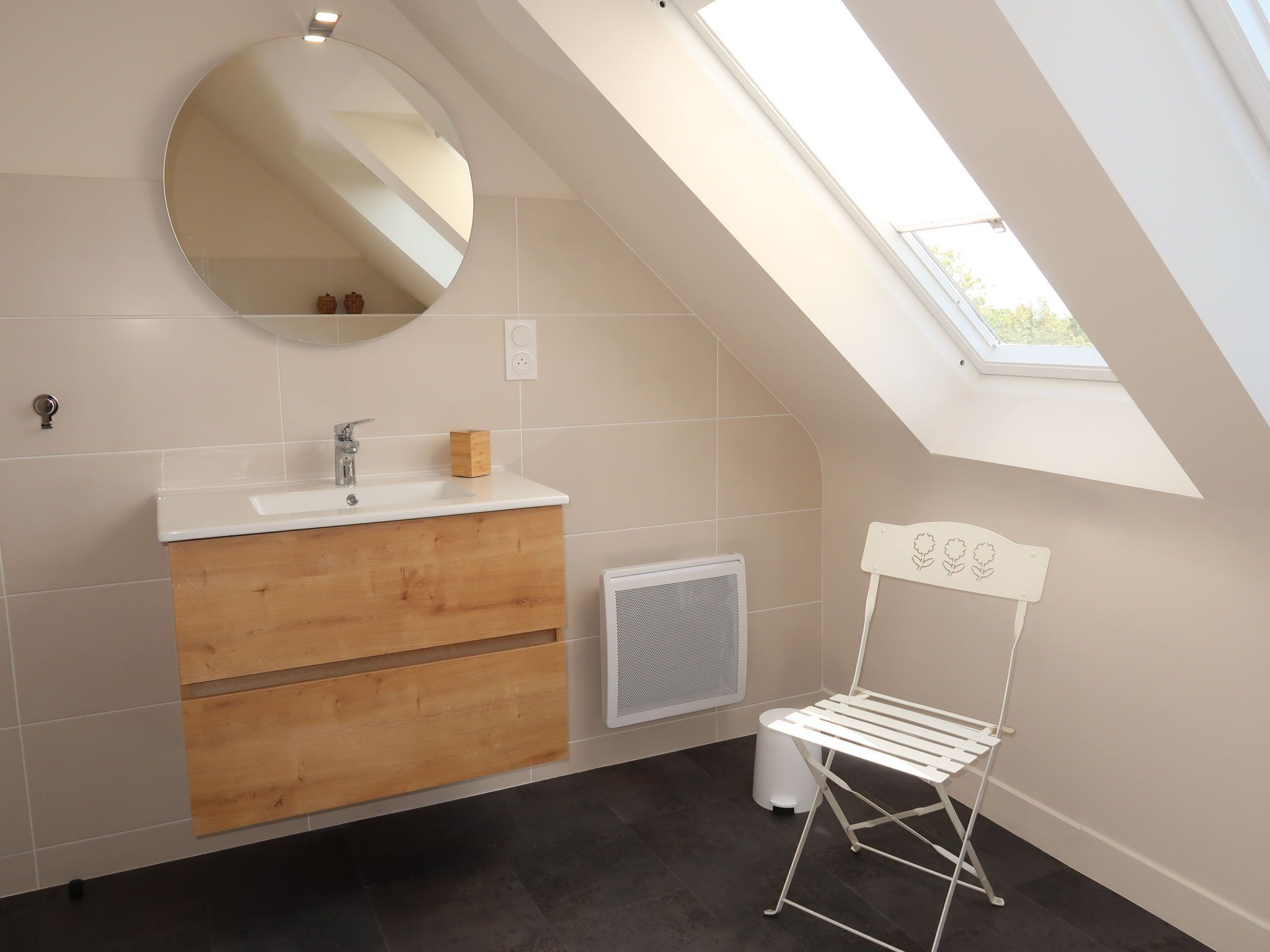 Un baño moderno con tragaluz, tocador de madera, espejo y tendedero.