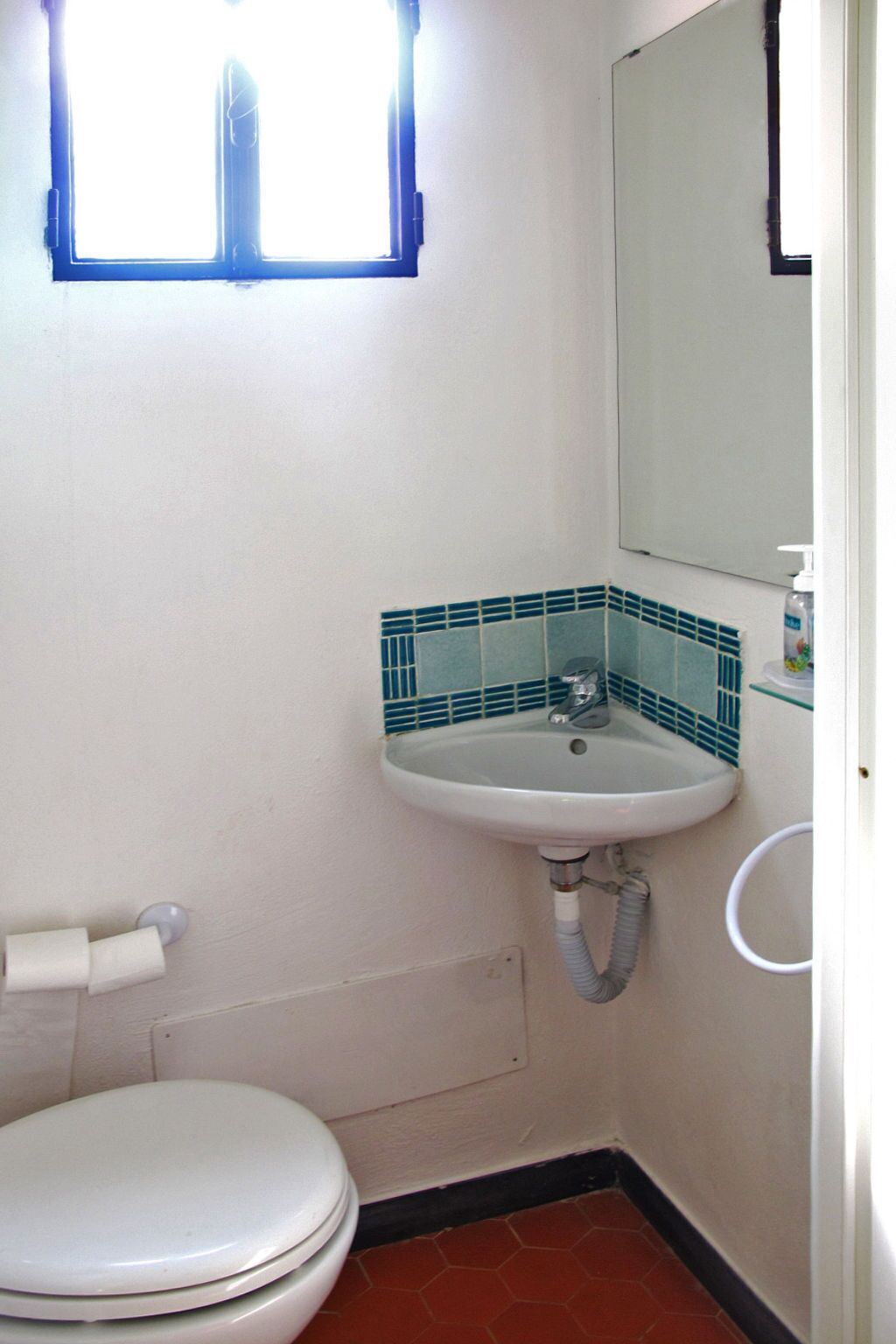 A small bathroom with a toilet, sink, and window.