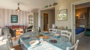 Un coin repas avec une nappe bleue, des chaises blanches et une variété d’articles de vaisselle.
