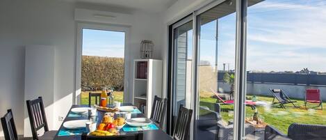 A dining area with a table set for four, a bookshelf, and a view of the backyard with outdoor furniture.