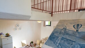 A dining area with a table set for two, a refrigerator, and a mural of a cityscape on the wall. - Annina & Maria Luisa (DOL287) by Interhome (Dolcedo)