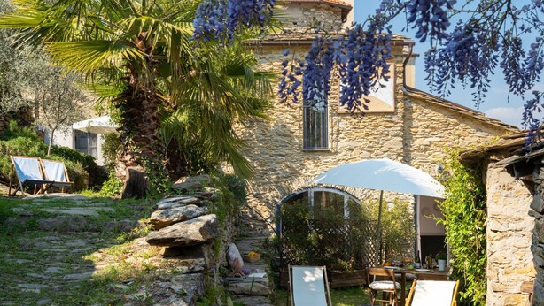 A stone building with a garden patio, outdoor seating, and a pergola. - Annina & Maria Luisa (DOL287) by Interhome (Dolcedo)