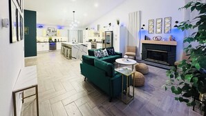 Un salón amplio con un sofá verde, una chimenea y una cocina al fondo.