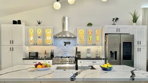 Una cocina moderna con una isla grande, muebles blancos y electrodomésticos de acero inoxidable.