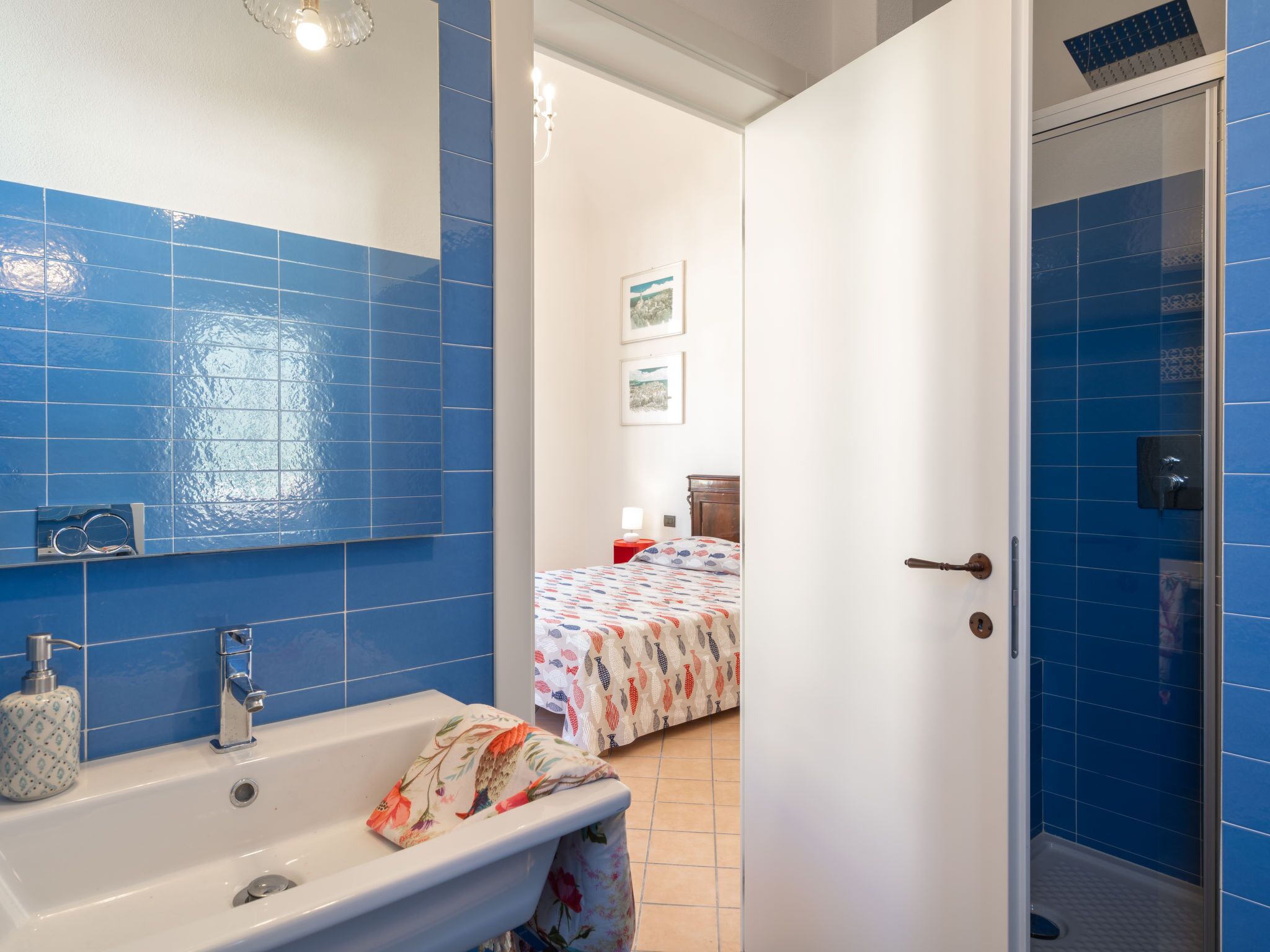 A bathroom with blue tiles, a white sink, and a shower area.