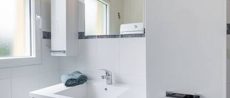 Een moderne badkamer met een witte wastafel, een spiegel en een handdoekhouder.