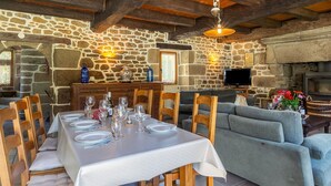 Un coin repas rustique avec des murs en pierre, des poutres en bois et une cheminée en pierre.