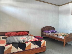 Ein Zimmer mit zwei Holzbett, eines mit floralem Überwurf und das andere mit einem geometrischen Muster.