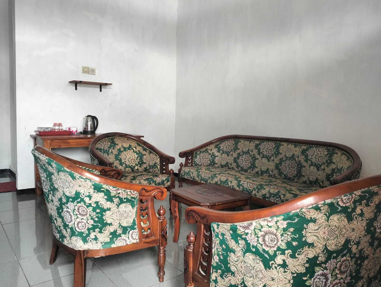 Una habitación con un conjunto de sofás, una mesa de centro de madera y una mesita con una tetera.
